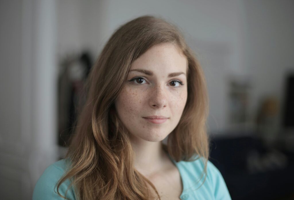 pexels-photo-3763188-3763188 Close-up portrait of a young freckled woman indoors, expressing calm and beauty.