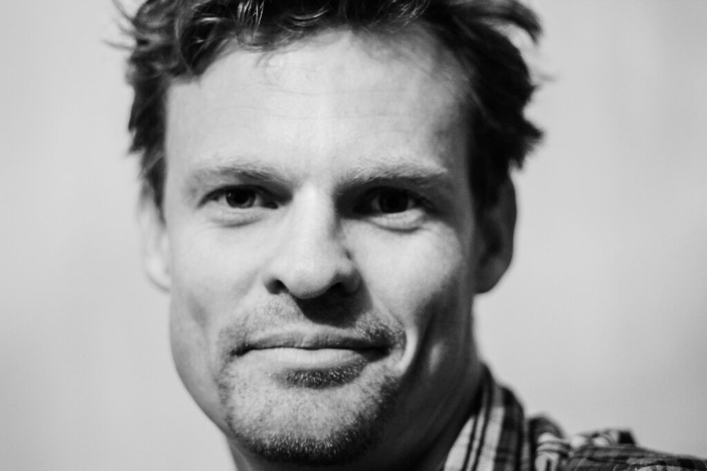 pexels-photo-634021-634021 Close-up black and white portrait showcasing a smiling man with facial hair.