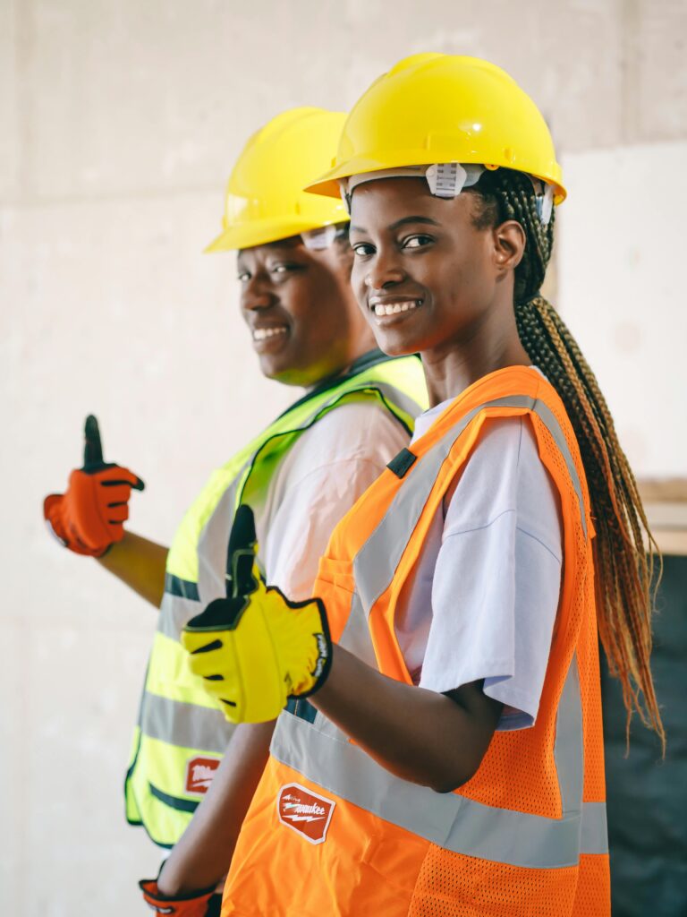 pexels-photo-8487390-8487390 Two smiling construction workers in PPE gear posing with thumbs up.